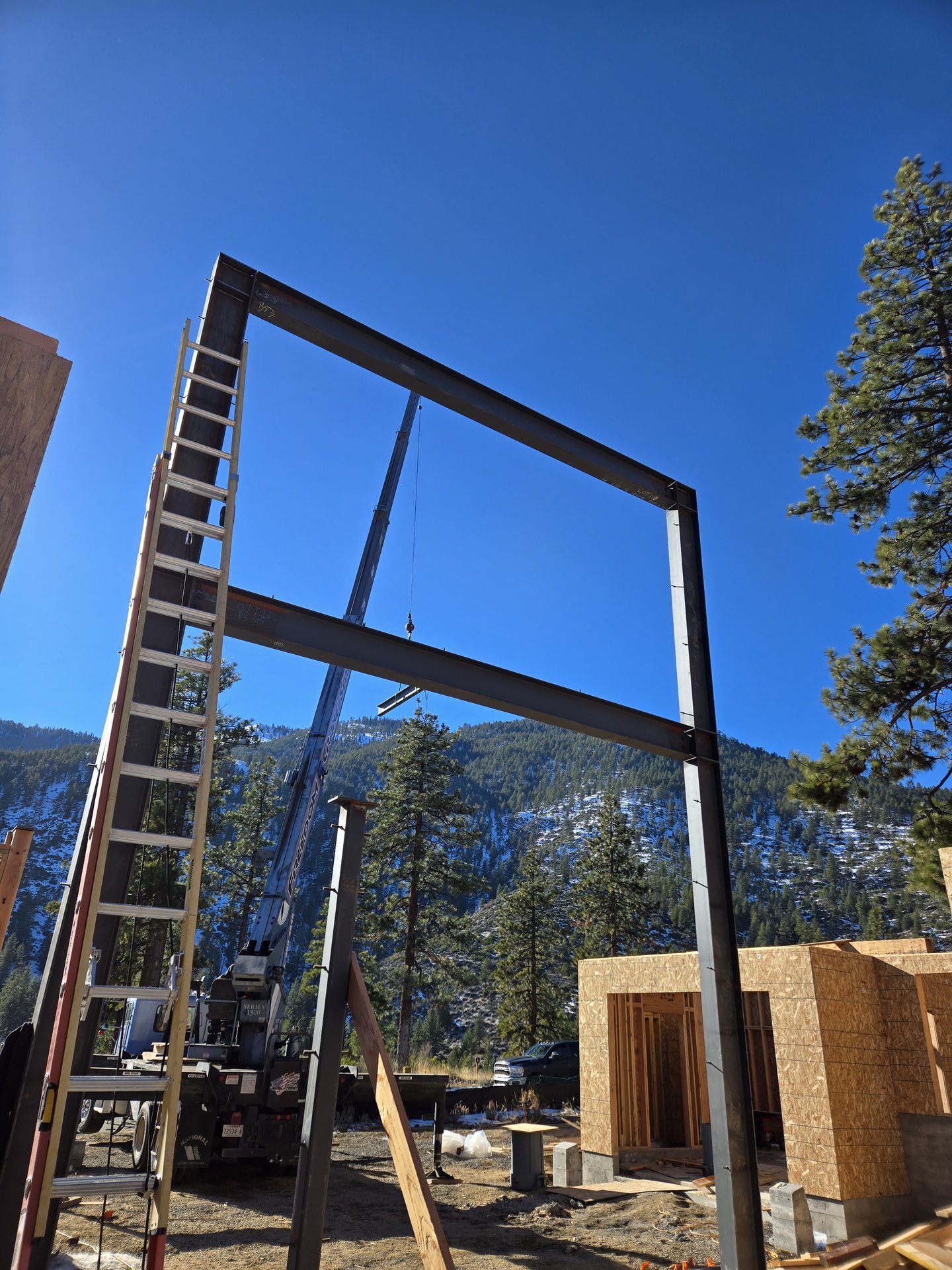 Structural steel portal frame set by crane on a Sierra Nevada custom home
